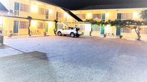 A two-story building with a car parked in front. There are multiple doors and windows, and the building is lit up at night. - Bradman Motor Inn (Cootamundra)