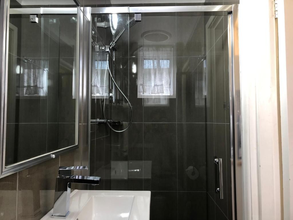 A modern bathroom with a glass-enclosed shower, a white sink, and a mirror.