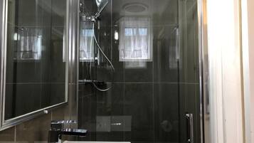 A modern bathroom with a glass-enclosed shower, a white sink, and a mirror.