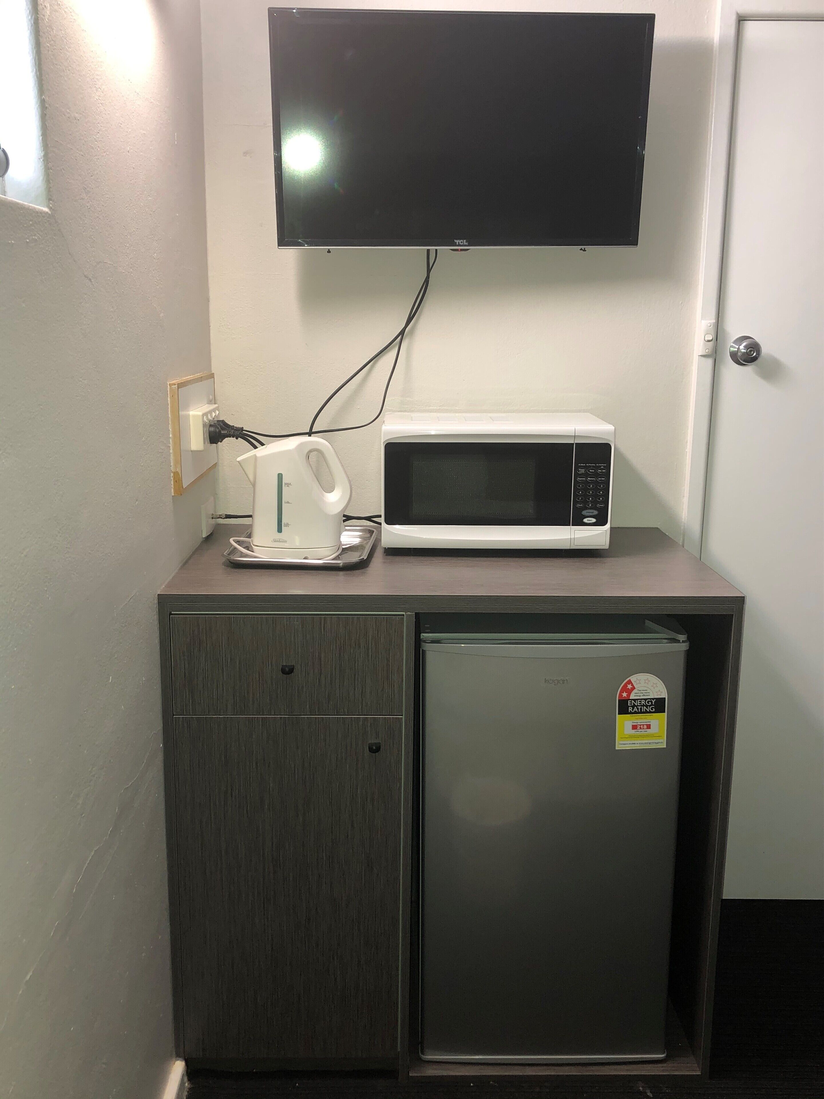 Una kitchenette equipada con microondas, hervidor y refrigerador.