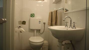 Un baño con inodoro, lavamanos y espejo.