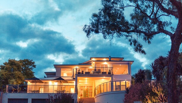 Una casa moderna de dos pisos con balcón, ventanas amplias y una entrada bien iluminada.
