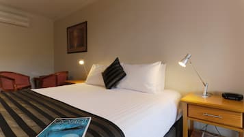 Una habitación de hotel con cama, escritorio, silla, lámpara y una revista sobre la cama.