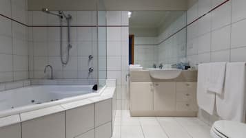 A modern bathroom with a large bathtub, a separate shower area, a vanity with a sink, and a toilet.