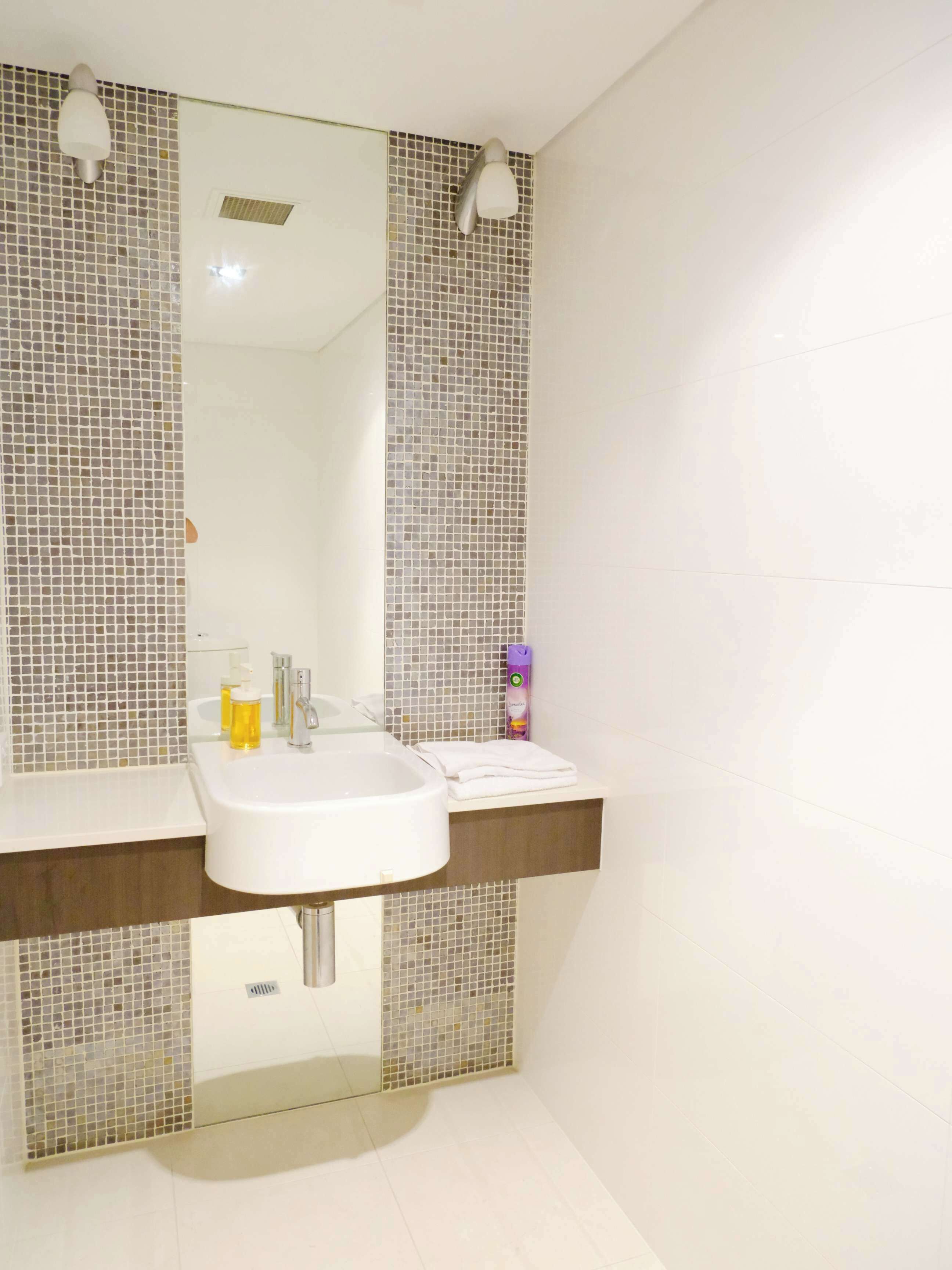 A bathroom with a white sink, two wall-mounted lights, and a mirror.