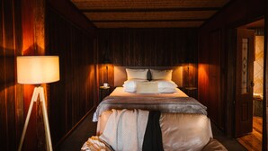 Una habitación con paneles de madera, una cama, una lámpara de noche y una mesita.