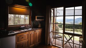 Una cocina con un ventanal grande, armarios de madera, microondas y vistas al exterior.