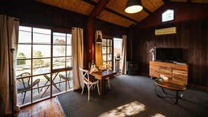 Una habitación con techo de madera, ventanas amplias, una mesa de comedor con sillas, un televisor y una chimenea.