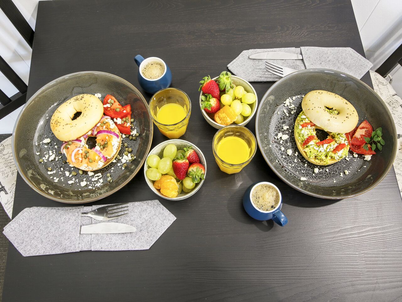 Una mesa de desayuno con dos tazones de comida, una taza de café y un bol de fruta.