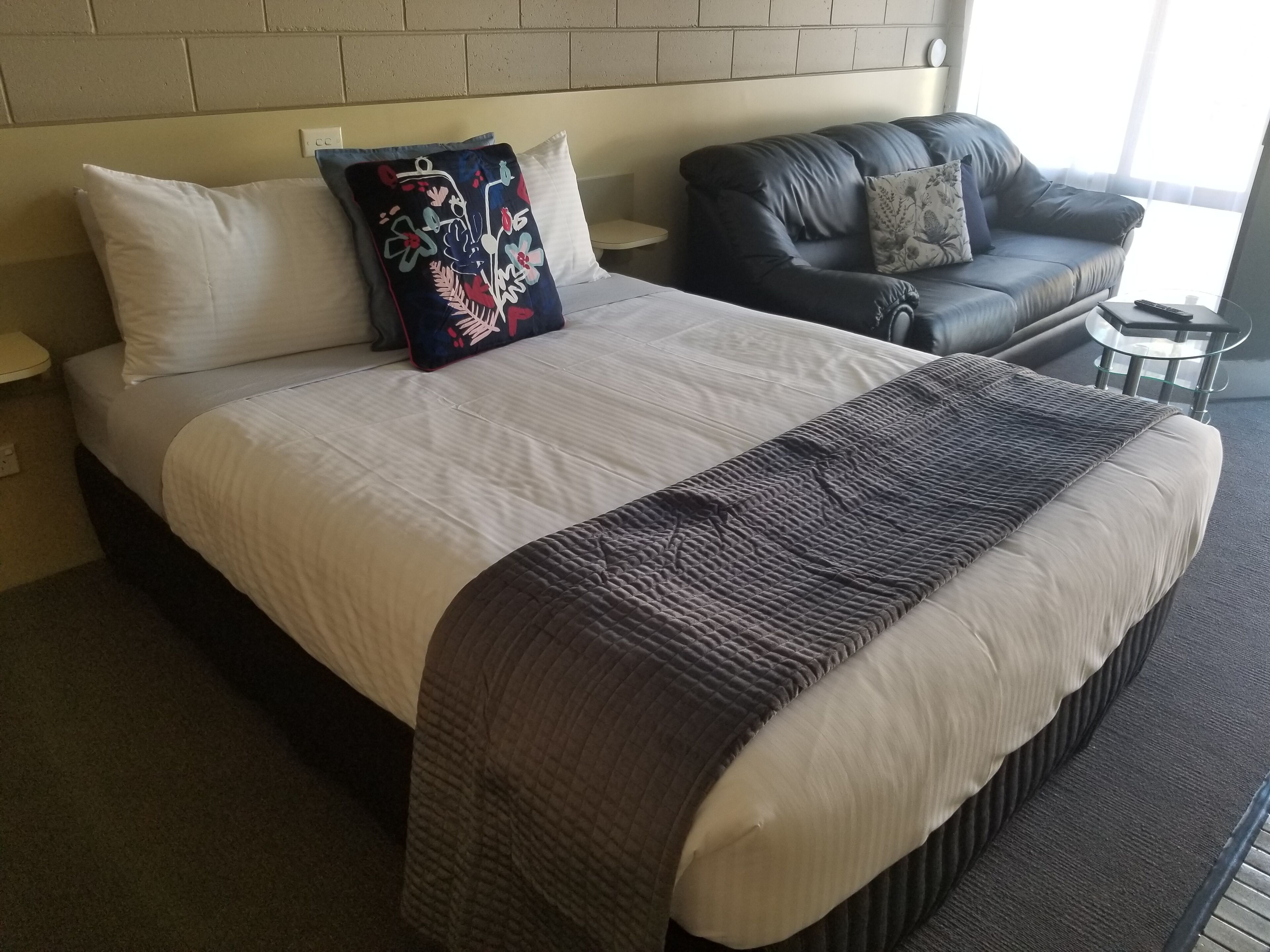 Une chambre d’hôtel avec un grand lit, un canapé en cuir foncé et une petite table ronde.
