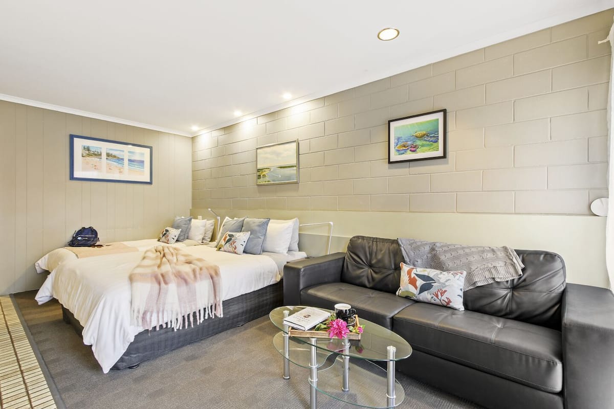 A modern hotel room with a bed, a sofa, and a glass coffee table.