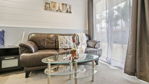 A modern living room with a leather sofa, a glass coffee table, and a cityscape artwork on the wall. - Sandbar Motel (Lakes Entrance)
