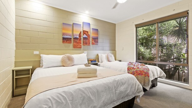 A bedroom with two beds, a large window, and a wall-mounted artwork. - Sandbar Motel (Lakes Entrance)