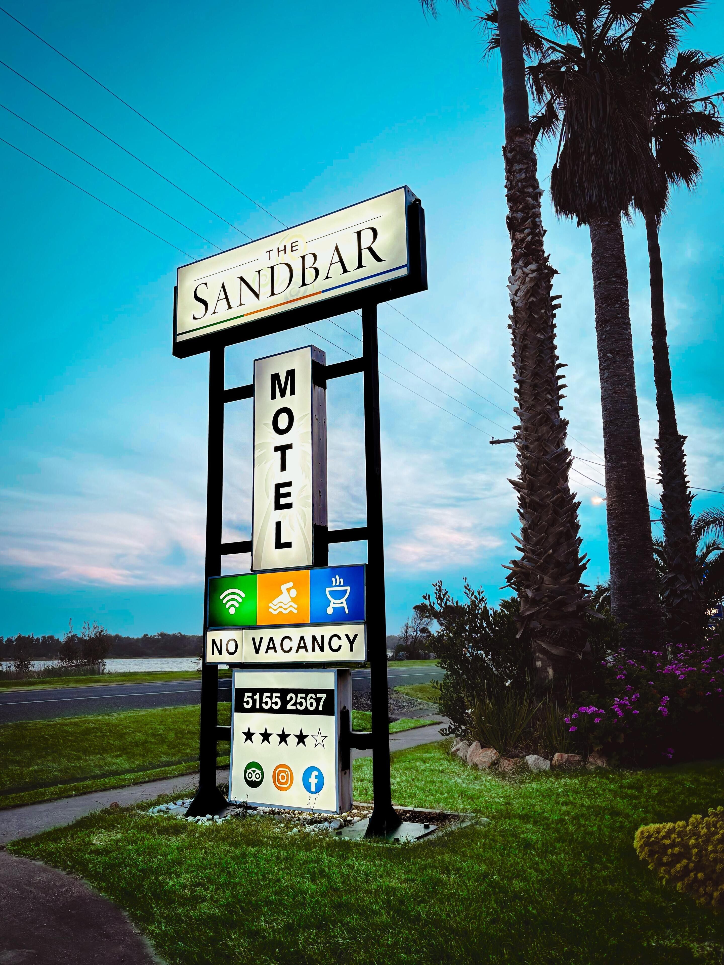 A motel sign with a 'NO VACANCY' notice, contact number, and icons for amenities like Wi-Fi, swimming, and BBQ.