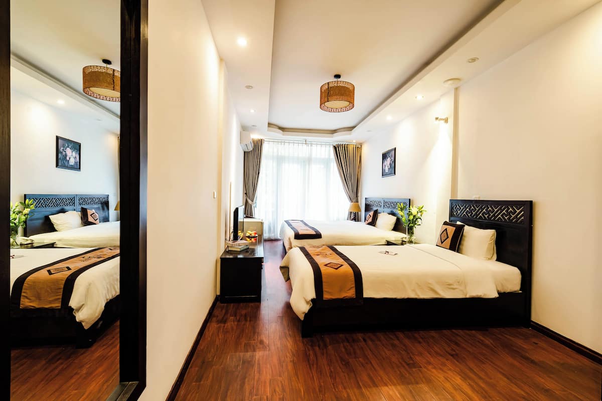 A hotel room with two beds, a large mirror, a desk, and a view of the city.