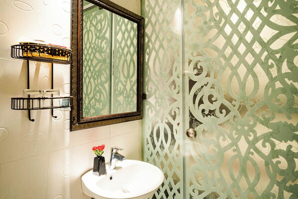 A bathroom with a white sink, a mirror, and a decorative shower door. - Wild Lotus Hotel & Travel 2 (Hanoi)
