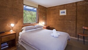 A bedroom with a bed, bedside tables, a nightstand, a window, and a framed picture on the wall. - Split Point Cottages (Aireys Inlet)