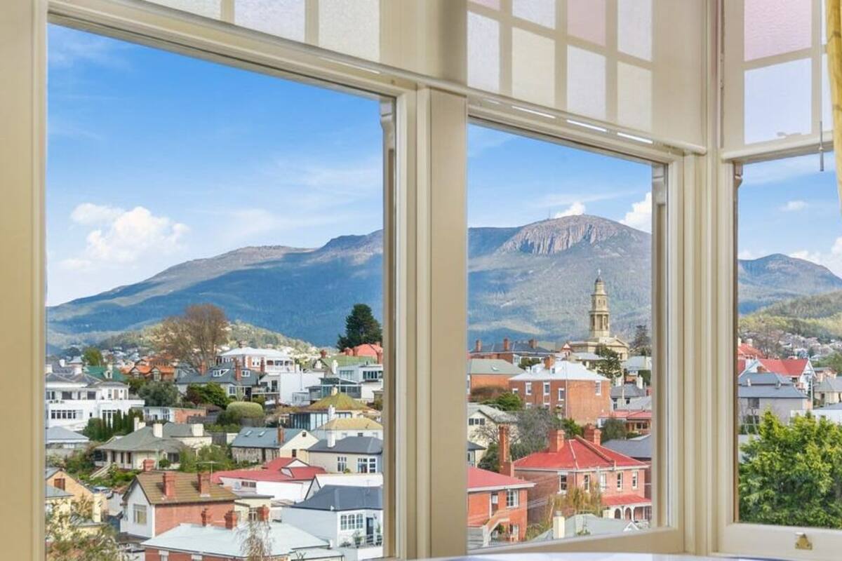 A view from a window overlooking a town with a prominent church and mountains in the background.