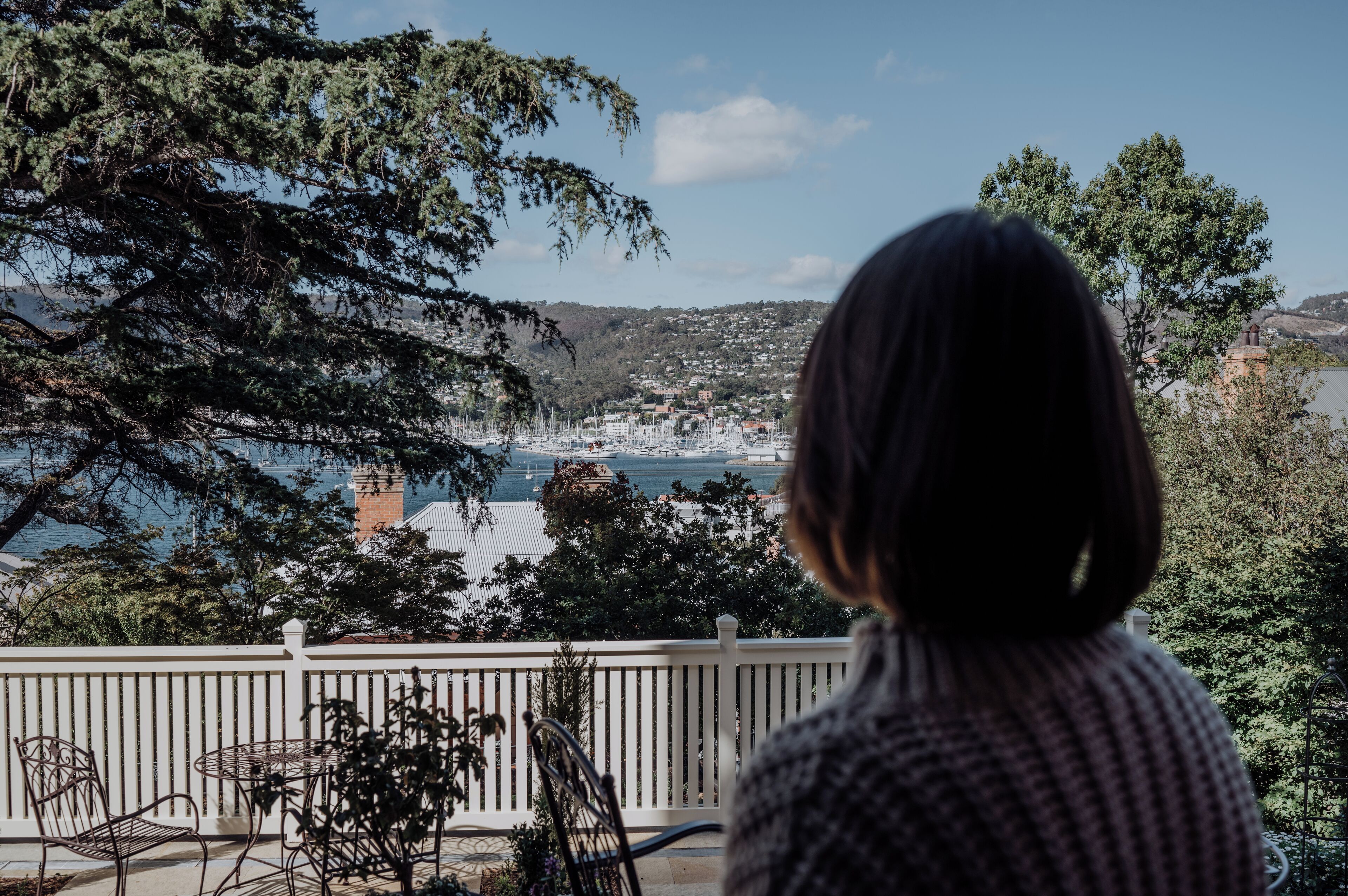 A person overlooking a coastal town with a view of boats and buildings.