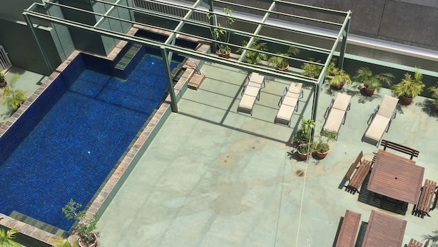 Un espace piscine extérieur avec une piscine bleue, des chaises longues et des plantes en pot.