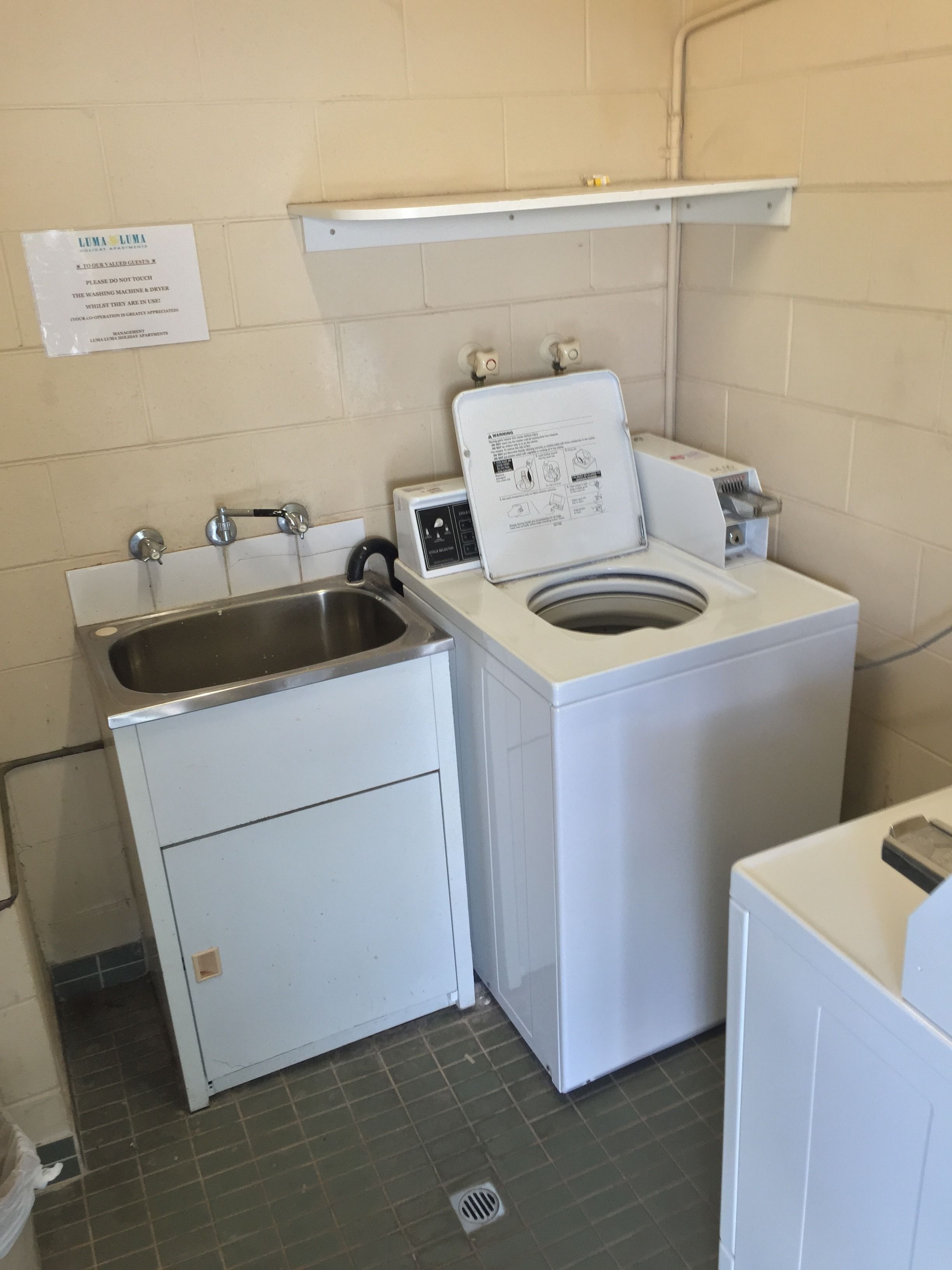 Un espace buanderie compact comprenant un lave-linge et un évier.