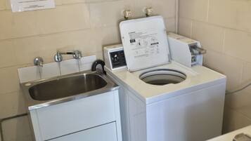 Un espace buanderie compact comprenant un lave-linge et un évier.