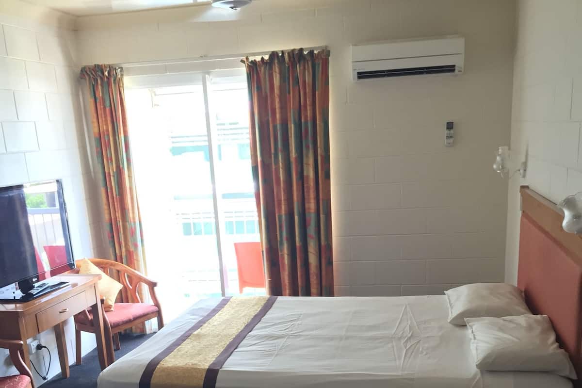 Een hotelkamer met een bed, een bureau met een computer, een stoel en een televisie.