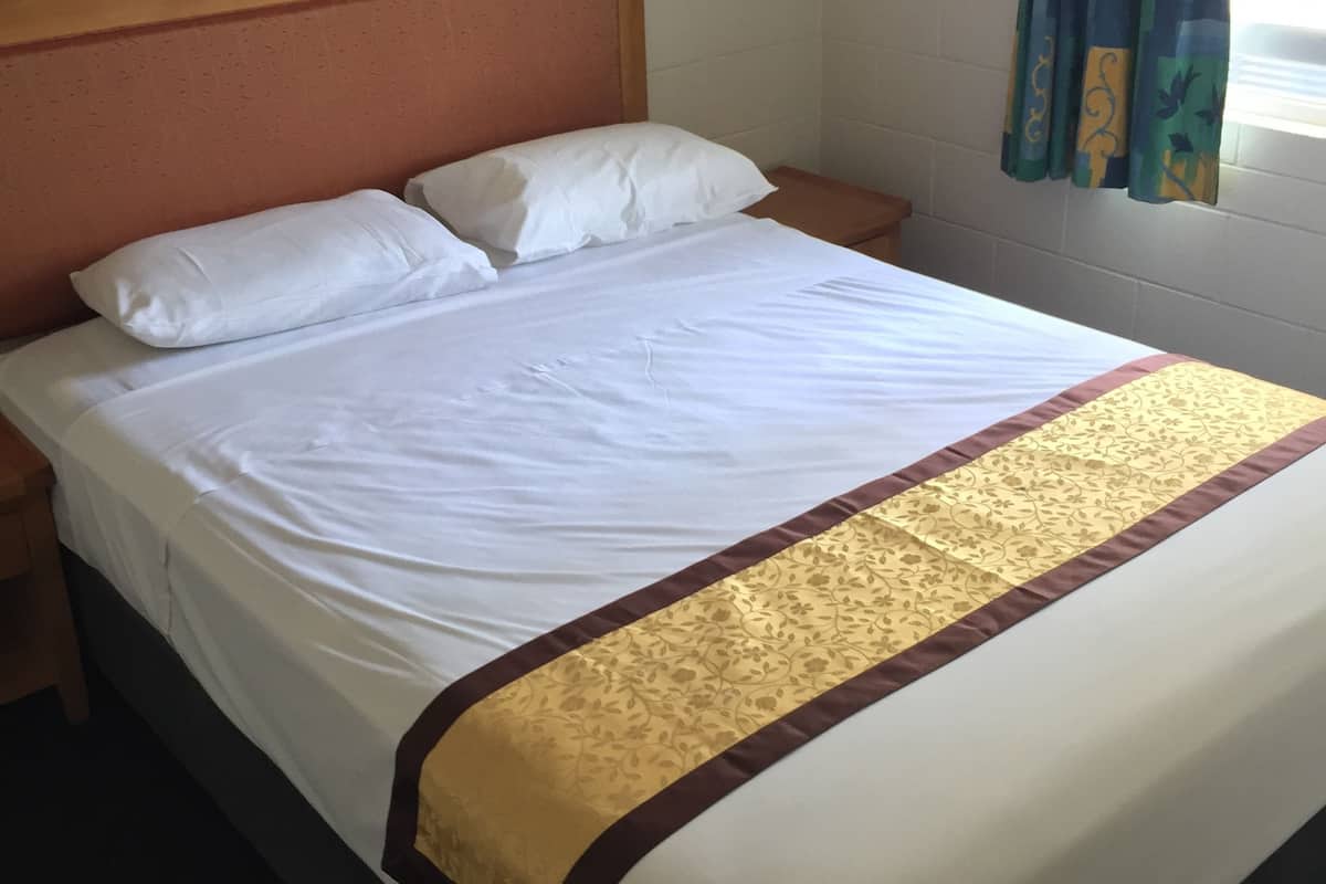 Een opgemaakt bed met witte lakens en een decoratieve gouden en bruine sprei.