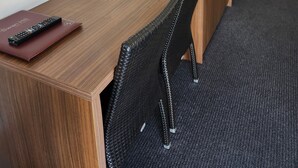 Une chambre d’hôtel avec un bureau en bois, un micro-ondes blanc, une télécommande et une chaise noire.