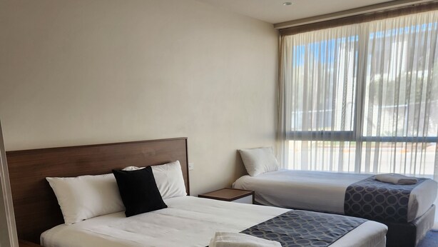 Une chambre d’hôtel avec deux lits, un ventilateur de plafond et une grande fenêtre avec des rideaux.