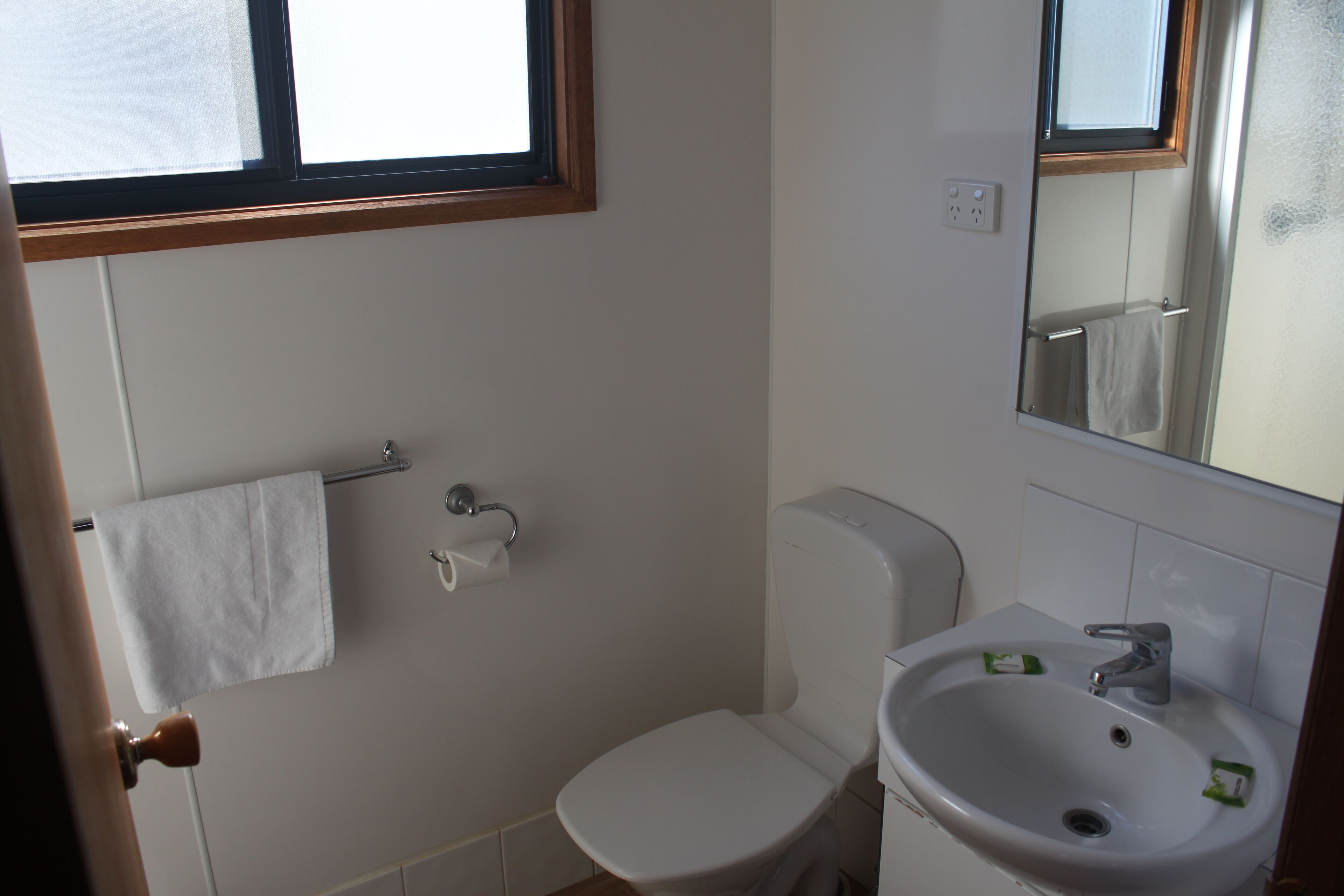 A bathroom with a toilet, sink, and a towel rack.