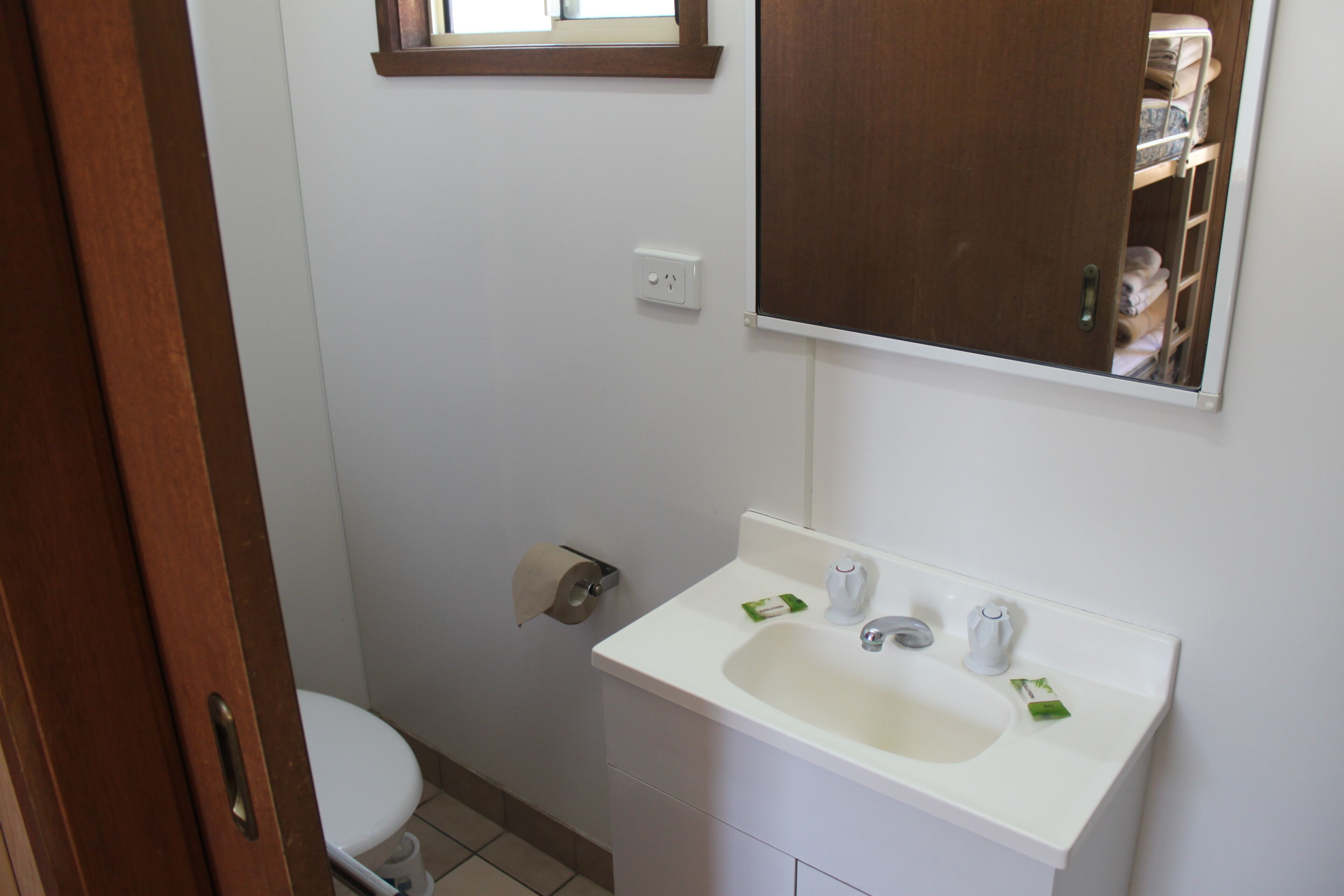A bathroom with a white sink, a toilet, and a mirror above the sink.