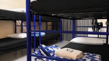 A bunk bed room with blue metal railings, a window with blinds, and a fan.