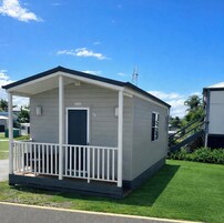 A single-story mobile home with a porch, a door, and a small window.