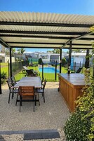 A covered patio with a pool, outdoor seating, and a bar area.