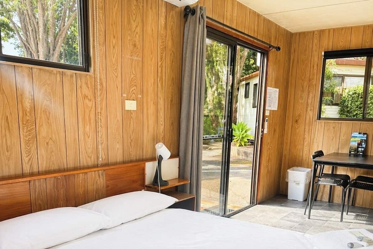 Una habitación de hotel con una cama grande, un escritorio y vistas a través de un ventanal.