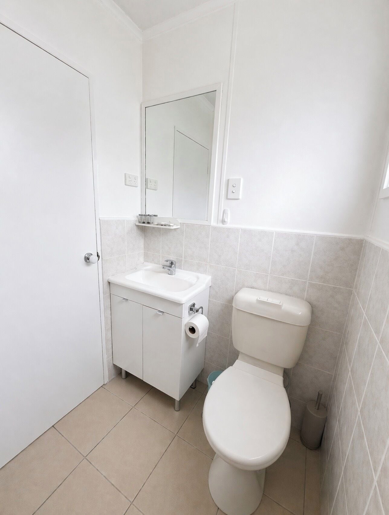 Un baño pequeño y limpio con inodoro, lavabo y espejo.