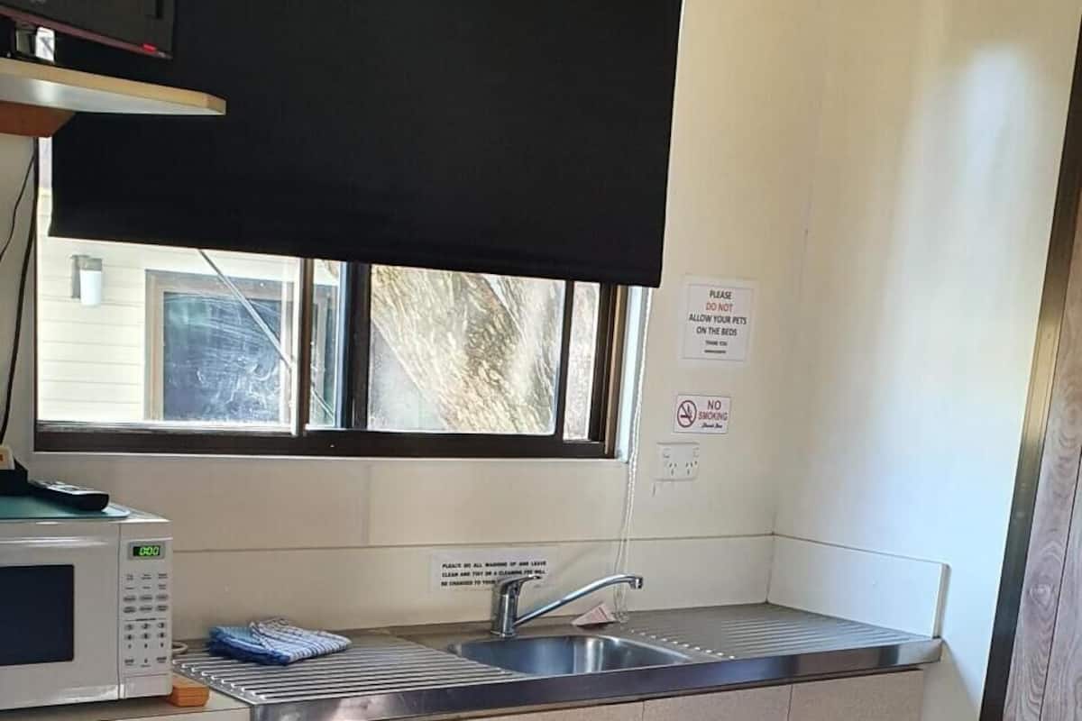 Una cocina compacta equipada con microondas, un refrigerador pequeño, un lavamanos y armarios.