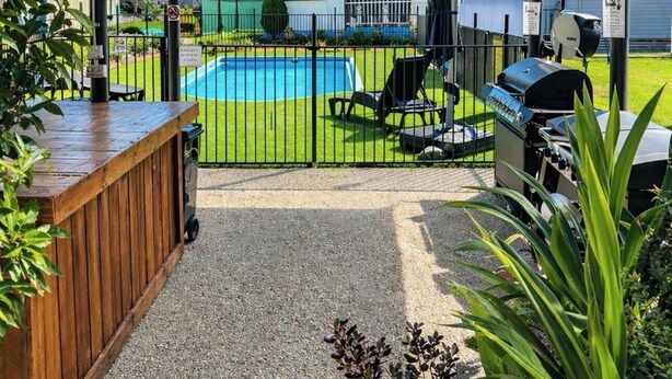 Un espacio al aire libre techado con piscina, sillas y una parrilla.