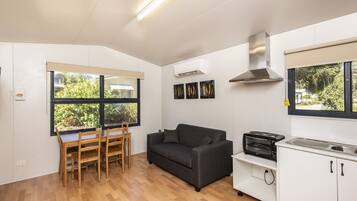 A compact kitchen with a dining area, a sofa, and a window with a view of greenery.