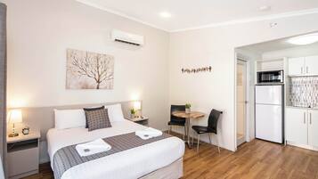 Ein Hotelzimmer mit einem Bett, Nachttischen, einem Schreibtisch mit Stuhl, einer Mikrowelle und einem Kühlschrank.