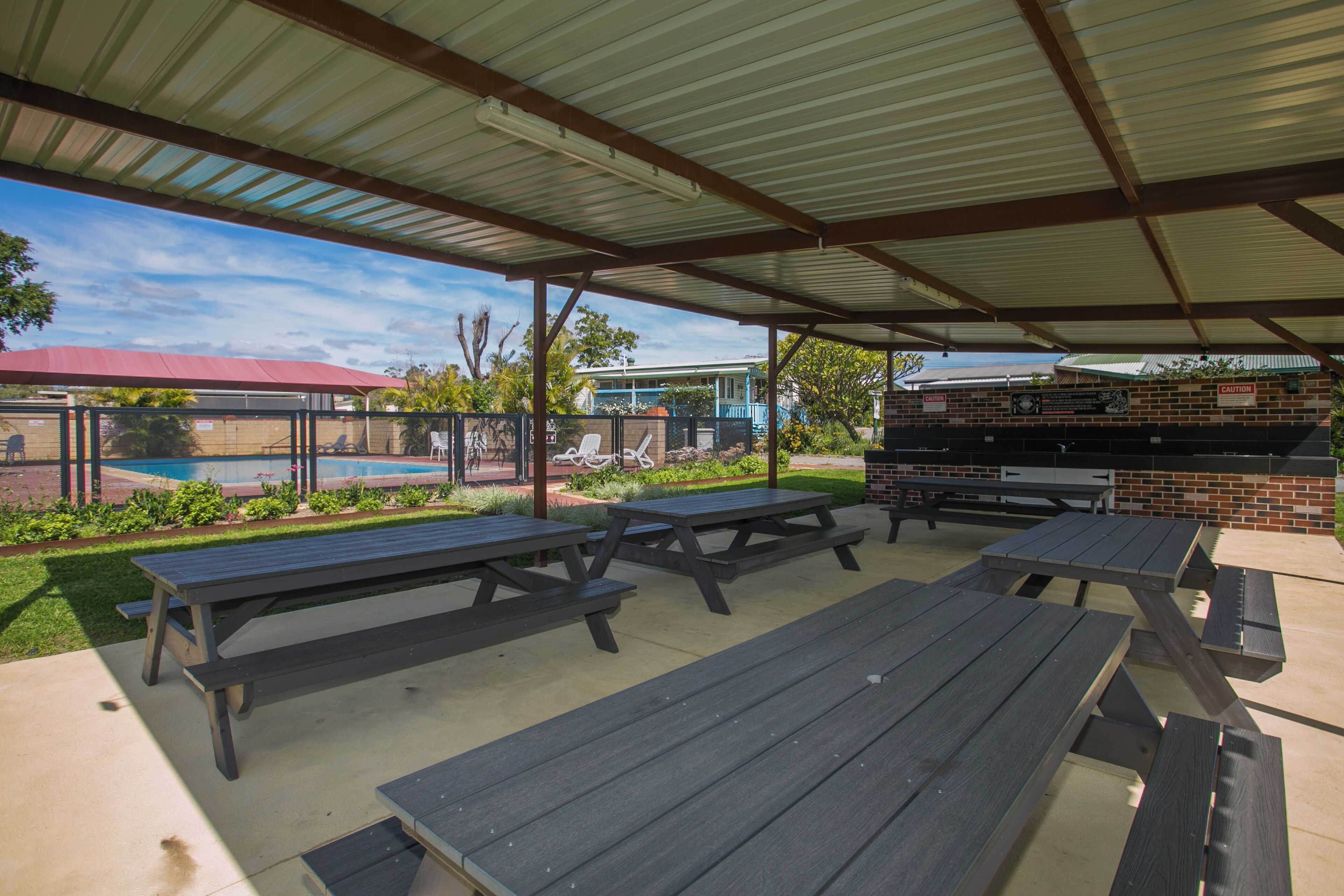 An outdoor patio area with picnic tables and a barbecue grill.