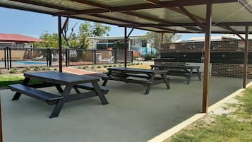 An outdoor patio area with picnic tables and a barbecue grill.