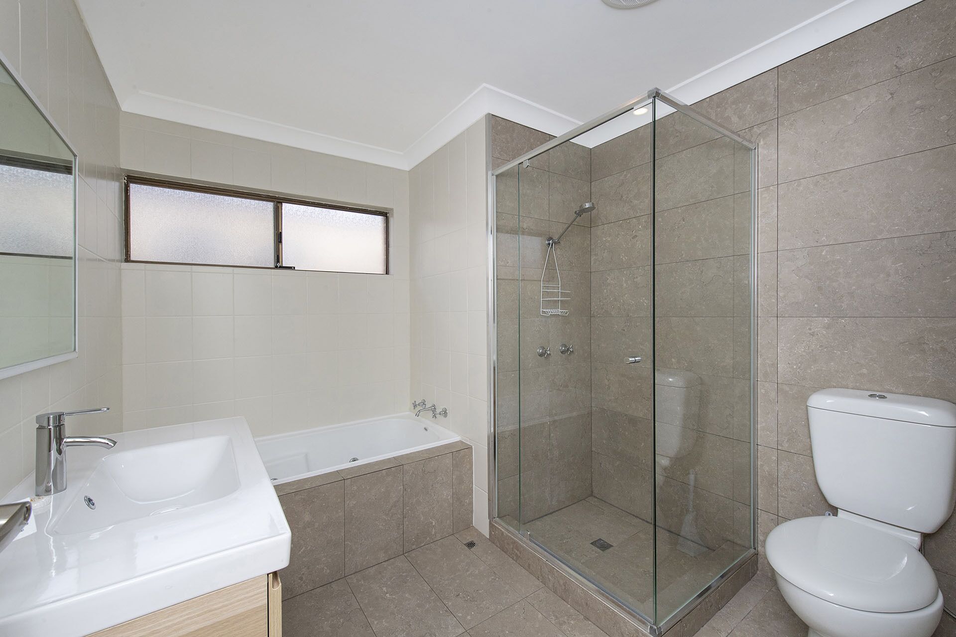 A modern bathroom with a glass-enclosed shower, a bathtub, and a toilet.