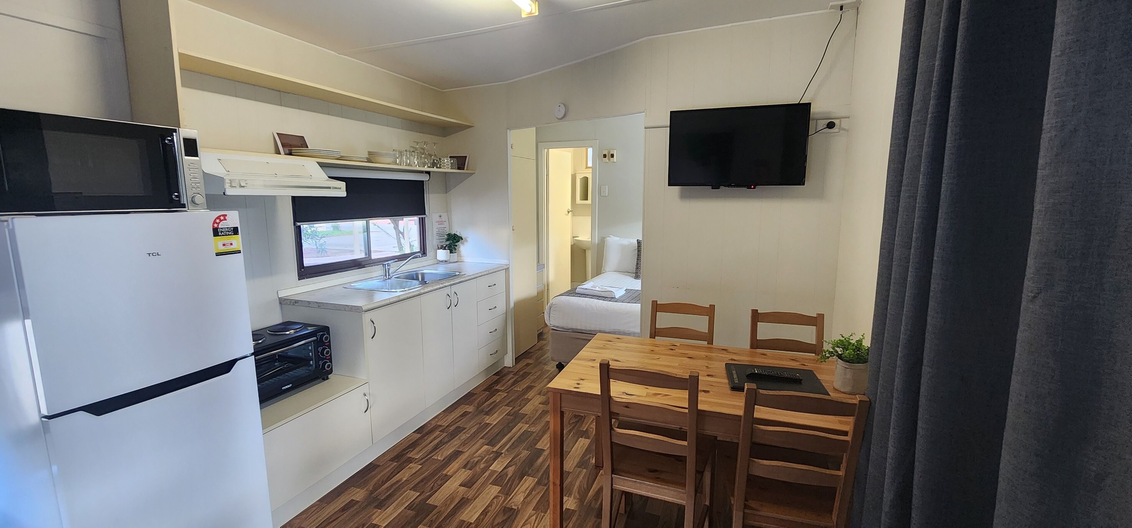 Cocina compacta con microondas, estufa, pileta y comedor con mesa y sillas.