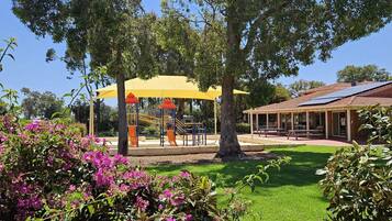 Relax in a serene outdoor setting surrounded by a well-maintained lawn and a shaded play area.
