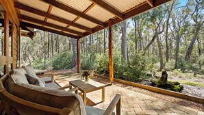 A covered outdoor seating area with a view of a forest. - Forest Rise (Yelverton)