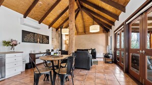 A spacious living area with a high ceiling, wooden beams, a dining table with chairs, a sofa, and a television. - Forest Rise (Yelverton)