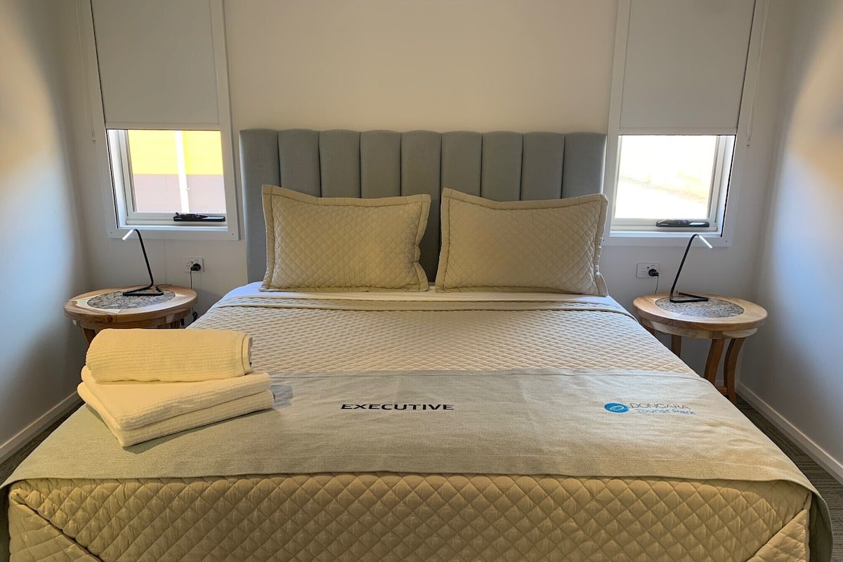 Ein Hotelzimmer mit einem Bett, zwei Nachttischen und zwei Fenstern.