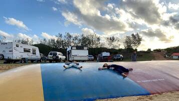 A recreational area with a trampoline, RVs, and a dirt path.